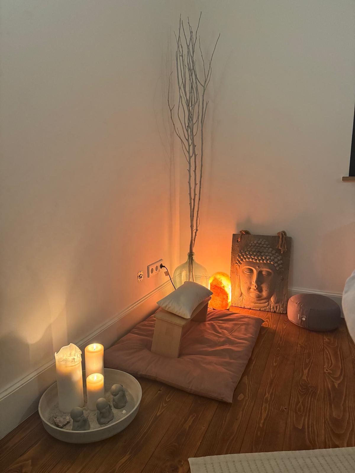 Meditationsecke mit Kerzen und Buddha in der Praxis Herz & Hände